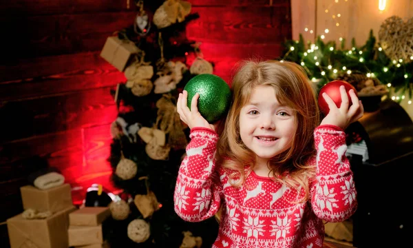 クリスマス タイム 新しい年 スノーフレークと鹿の赤いジャケットの小さな女の子 ホリデーコンセプト 冬のセーターで幸せな少女プリスクーラーは赤と緑のクリスマスツリーボールを保持しています — ストック写真