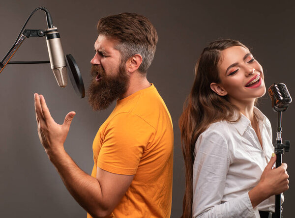 Happy couple in recording studio. Music performance vocal. Singer singing song with a microphone