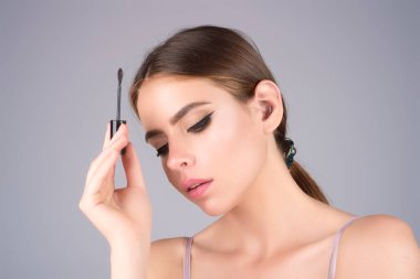 Eyebrow shaping, woman combs eyebrows with a brus. Eyebrow line. Makeup and cosmetology concept. Female model with long eyelashes and thick eyebrows. Perfect shaped brow