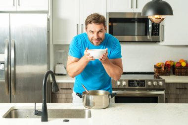 Aşçı mutfakta yemek pişiriyor. Şef aşçı tencereli bir yemek hazırlıyor. Menü tarifi sağlıklı yemek. Şef modern mutfakta yemek pişiriyor. Olgun aşçı mutfakta yemek hazırlıyor.