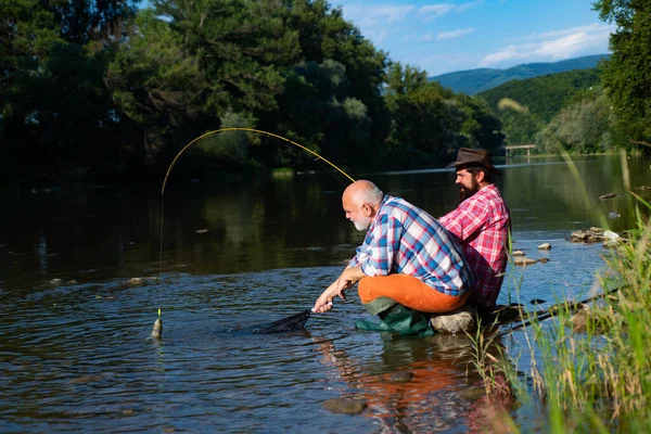 Mature senior man with friend fishing. Summer vacation. Happy cheerful people. Bearded men catching fish. Fisherman with fishing rod. Activity and hobby. Catching trout fish