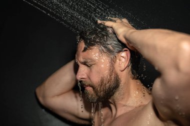 Milenyum adamı banyoda saç yıkıyor. Küvette banyo yapan adam. Yüzü duşta köpüklü. Banyo yapan adam duş alıyor. Yakından duş alan adam. Duş konsepti. İnsan duşta su altındadır.