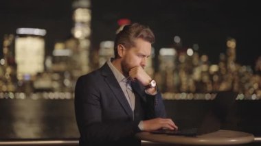 Night City 'de çok çalışan bir iş adamı. Çok çalışan adam dışarıda dizüstü bilgisayarda çalışıyor. Gece sokağındaki iş adamı. Çok çalışan bir ofis çalışanı. İşadamı geceleri laptopunu kullanarak dışarıda çok çalışıyor.