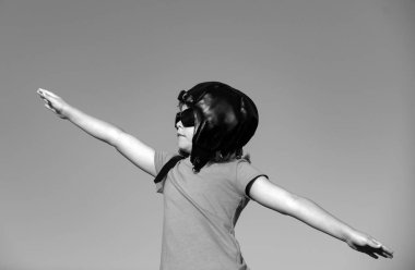 Uçma hayalleri. Gökyüzüne karşı pilot gözlüklü ve kasklı çocuk. Seyahat hayalleri. Oyuncak uçağı olan rüya gören küçük çocuk dışarıda oynuyor.