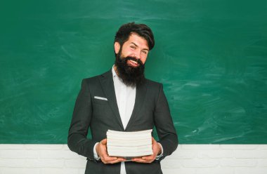 Öğretmenler günü - bilgi ve eğitim okulu kavramı. Ciddi erkek öğrenci okulda okuyor. Okul konsepti