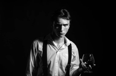 Klasik giyimli şık ve şık bir adam ve bilge bir adam. Bir bardak viski tutan şık, zengin bir genç adam.