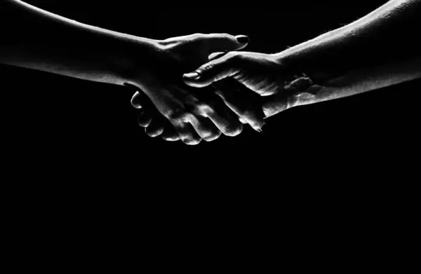 Handshake between the two partners. Rescue or helping gesture of hands. Concept of salvation. Hands of two people at the time of rescue, agreement, help. Isolated on black background