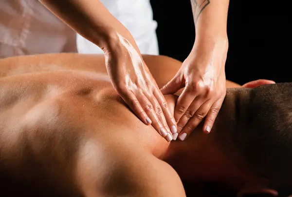 Massage for man. Physiotherapist massaging male shoulder