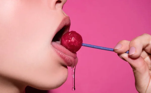 Orgasm concept. Lollipop in woman mouth, red lipstick. Woman licking a red shiny lollipop. Close up. Sexy woman with lollipop in sexy mouth