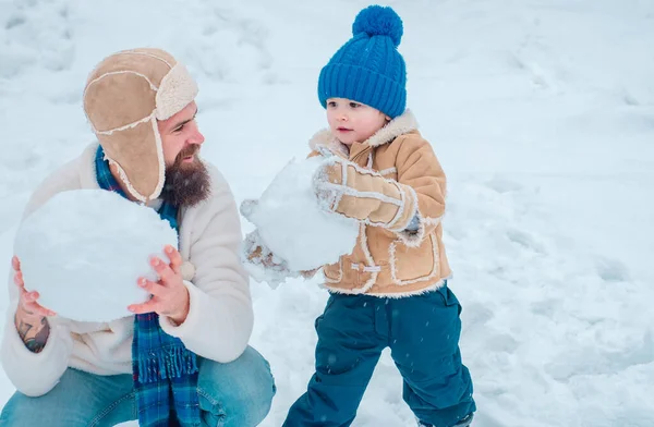 雪上の冬の散歩に雪だるまと遊ぶ幸せな家族 冬の白地で雪玉を作る父と息子 — ストック写真