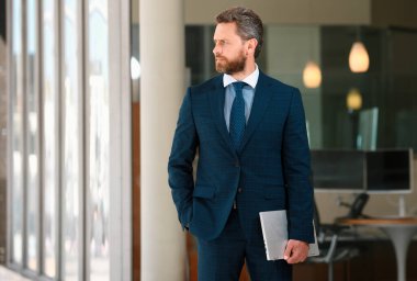 İş adamının elinde dizüstü bilgisayar vardı. İş yerinin yakınında duruyordu.
