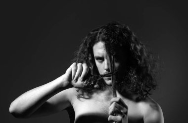 Genç seksi adam, makaslı adam portresi uzun kıvırcık saçlı. Modern berber dükkanı, tıraş. Modern saç stili siyah olan yakışıklı bir erkek.