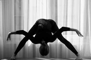 Bale dansçısı. Ev antrenmanı. Kadın jimnastikçi, jimnastik akrobatı. Bir kadın evde egzersiz yapıyor. Kadın evde yerde esneme egzersizleri yapıyor.