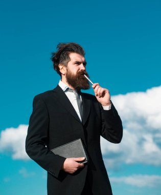 İşadamı kalemle ilgili bir şey düşünüyor. İş hayalleri. Takım elbiseli iş adamı.