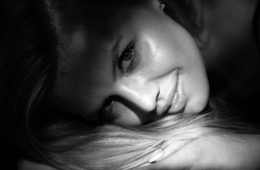 Sarışın, gülümseyen, yakından bakan kız. Güzel yüzlü manken. Siyah arka planda şefkatli bir kadın. Şefkat kavramı. Şefkatli kadınlar gibi. Güzellik ve şefkat kavramı