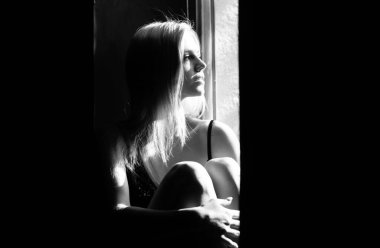 Güzel yüzünde gölgeler olan şehvetli bir kadın. Pencerenin yanında şehvetli bir kız