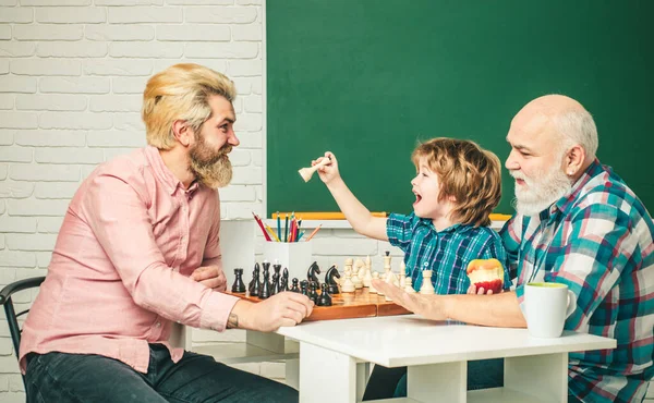 Grandfather father and son playing chess, men in different ages ready to study. Happy family at school. Three men generation