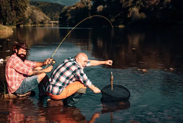 一个快乐的老人钓鱼的画像 祖父和儿子是渔夫 年轻人和老人在河里或湖中钓菠萝 — 图库照片