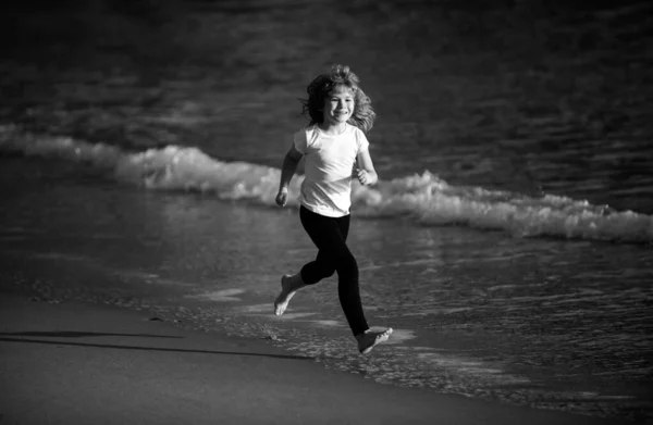 Happy boy run to the sea. Child have fun on beach, run by sea water pool. Summer vacation with child