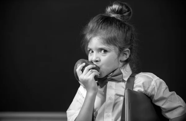 クラスの小さな女子学生 学校でリンゴを食べています 面白い子供たちが近づいてくる — ストック写真
