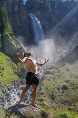 Şelaledeki adam. Seksi bir adam. İnsan özgürlüğü yaşam tarzı. Doğada meditasyon. İspanyol adam yoga yapıyor. Yaşam tarzı rahatlama konsepti, yaz meditasyonu. Sakin ol ve doğada rahatla.