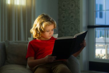 Kitabı olan bir okul çocuğu. Genç çocuk evde yalnız kırmızı kitap, çocukluk