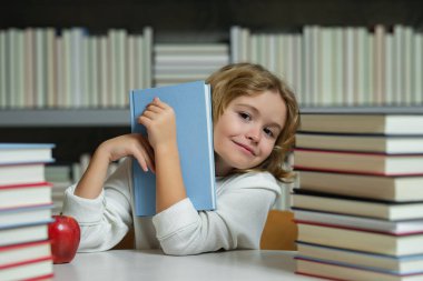 Okullu çocuk. Çocuk eğitimi ve okul konsepti. Kütüphanede kitap okuyan öğrenci portresi. Çocuk gelişimi, okumayı öğrenmek. Kitapçıda kitap okuyan bir çocuk