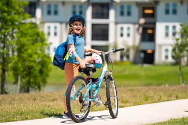 Küçük çocuk yaz parkında bisiklet sürüyor. Çocuk dışarıda bir garaj yolunda bisiklet sürüyor. Şehirde kask takan bisikletli bir çocuk. Bisikletli çocuk dışarıda. Amerikan mahallesinde bisiklet süren bir çocuk.
