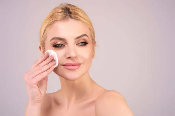 Woman with cotton pad. Toner for cleaning make up. Clean healthy skin, studio background. Beauty woman holding cotton pad, applying cleansing lotion facial wipe on face, removing makeup