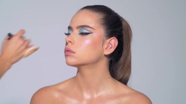 Makyöz, güzellik kraliçesinin yüzüne tonal fondöten uyguluyor. Makyaj yapma süreci. Makyaj sanatçısı ve kozmetik fırçası. Güzellik salonunda genç bir kadının portresi.