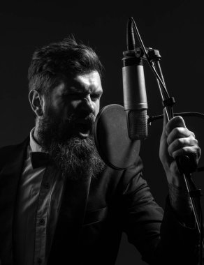 Kayıt stüdyosunda şarkı söyleyen adam. Mikrofonlu etkileyici sakallı adam. Klasik şarkıcı, müzik vokalisti.