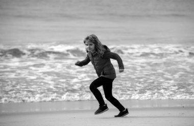 Çocuklar dışarıda koşuyor. Koşmak ve çocuklar için sağlıklı spor. Denize yakın koşan bir çocuk, spor yapan çocuklar. Küçük bir koşucu egzersizi. Çocuklarla sabah koşusu