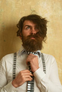 Komik bir hippi portresi. Kravatını bağlayan beyaz gömlekli komik sakallı adamın portresi. Taranmamış dağınık saçlı sakallı adam. Çılgın sabah