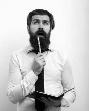 Elinde kalem ve defterle, beyaz arka planda izole edilmiş yakışıklı, şaşırmış bir adam.