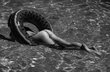 Summer Vacation. Enjoying suntan. Woman in bikini on the inflatable mattress in the swimming pool. Sexy legs and ass buttocks in pool