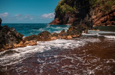 Kıyısında ve sularında büyük kayalar olan güzel bir okyanus sahili. Okyanustaki dalgalar. Yaz tatili, tatil. Red Sand Beach, Maui in Hawaiian