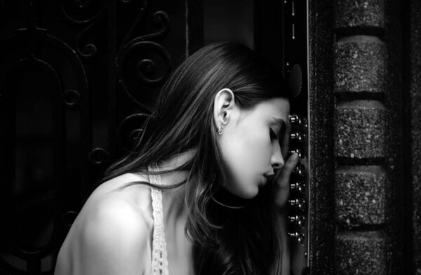 Sad pensive woman in depression. Self isolation. Home safety concept. Woman intercom code button. Lady female doorbell at building entrance