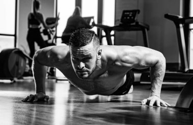 Formda bir adam. Çıplak gövdeli genç kaslı adam spor salonunda çalışıyor. Spor adamı şınav çekiyor, şınav çekiyor. Spor konsepti