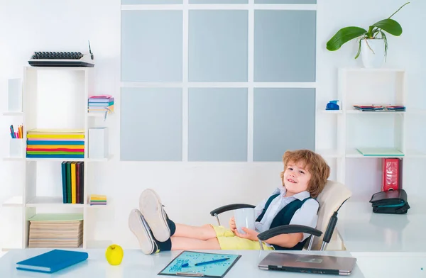 Office life. Little kid boy businessman wearing in formalwear reading document and standing in office. Businessman child in office relaxing in chair. Funny kids