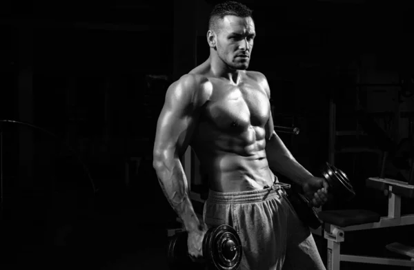 スポーティライフスタイル ジムでダンベルと強い男の運動 男性の裸の胴 ６パック — ストック写真
