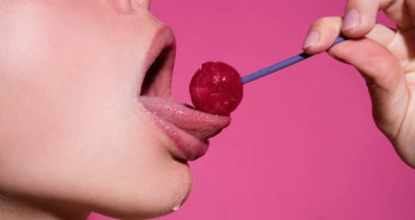Dudaklarını yalıyor. Pembe dudakları olan, lolipop tutan seksi bir kadın ağzı, güzellik kapanışı. Seksi kız lolipopu yaladı. Güzellik konsepti, yakın plan.