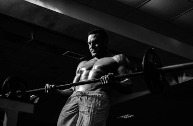 Spor yaşam tarzı konsepti. Spor salonunda spor yaparak kas çalıştıran üstsüz vücut geliştirici. Çıplak atletik vücudu olan bir sporcu. Sportif egzersiz.