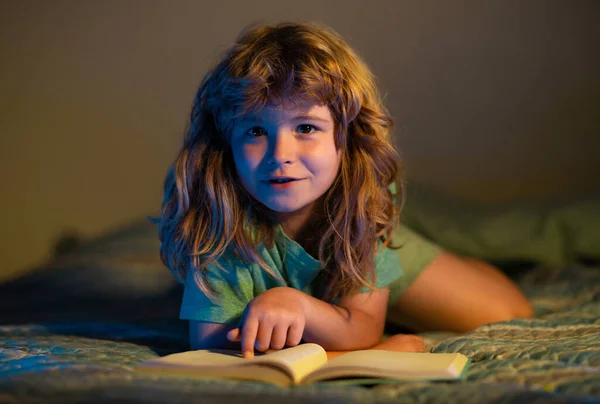 子供の少年は本を読む 知識に向かって 本を持っている少年は暗い部屋の背景の上に物語を読む 子供は勉強と読書を楽しむ 読むことができる子供の本 児童文学 — ストック写真
