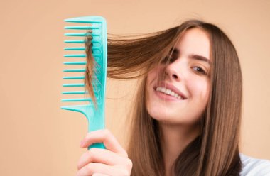 Saçını tarayan, gülümseyen güzel bir genç kadının portresi. Tarakla sağlıklı saç tarayan bir kadın.