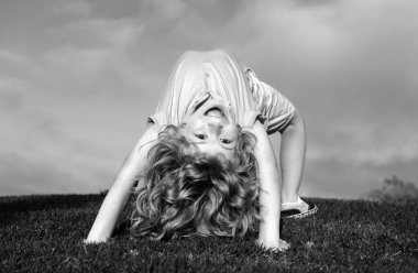 Egzersiz yapan komik şirin çocuk. Mutlu çocuk bahar parkında yeşil çimlerde oynuyor.