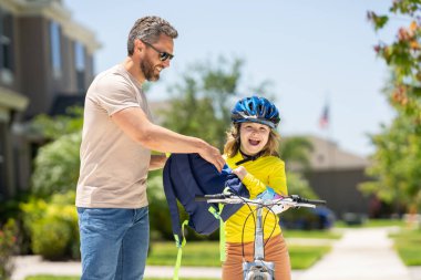 Babalar Günün kutlu olsun. Baba oğluna bisiklet sürmeyi öğretiyor. Baba heyecanlı oğluna Amerikan mahallesinde bisiklet sürmesi için yardım ediyor. Bisiklet kasklı çocuk babasıyla bisiklet sürmeyi öğreniyor. Babalar Günü