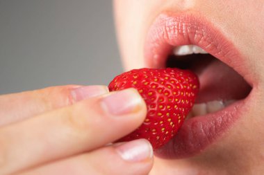 Çilek yalıyorum. Çilekli makroyu ısır. Şehvetli bir ağız. Çilek yiyen kadın şehveti. Şehvetli seksi kadın ağzı Çileği yakın mesafeden yala
