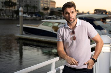 Dışarıdaki yakışıklı erkek modelin portresi. Polo giymiş şık bir adam. Moda erkeği sokakta poz veriyor. Şehir tarzı. Genç adam şehirde yürüyor. Yanında poz veren varlıklı iş adamı