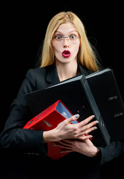 Secretary deluged by documents. Thoughtful young Secretary holding folders on black background. Businesswoman or Secretary hold many folders with documents, paperwork. Busy secretary accountant