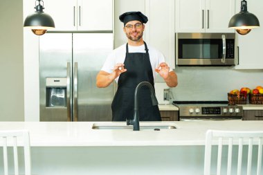 Mutfakta şef üniforması giyen yakışıklı orta yaşlı bir adam. Aşçılık ve aşçılık. Restoran menüsü konsepti. Yemek servisi, yemek pişirme, yemek reklamcılığı. Üniformalı adam mutfakta.